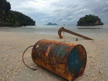 Rusty metal on beach against sky