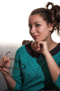 Portrait of confident beautiful woman holding eyeglasses