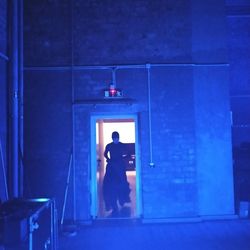 Rear view of man standing against blue door