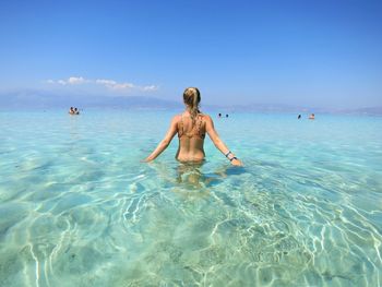 Rear view of woman on beach against blue sky