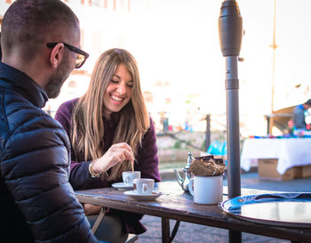 Couple with coffee on table talking while sitting at outdoor cafe