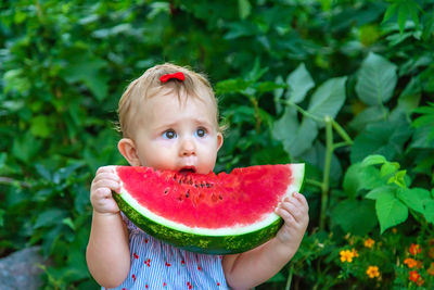 Cute girl eating watermelon against plants