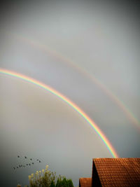 Low angle view of rainbow over building against sky