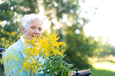 Side view of young woman smelling flowers