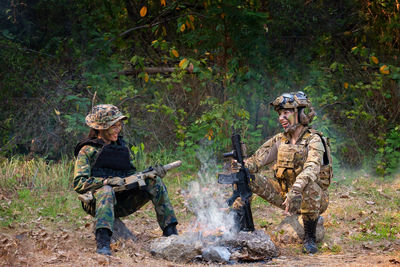 Smiling female soldiers sitting at campfire