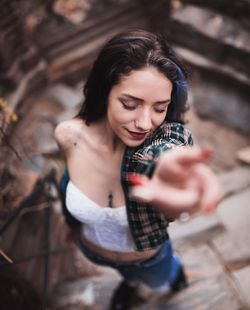 High angle view of young woman with hand raised standing outdoors