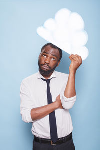 Portrait of young man standing against sky