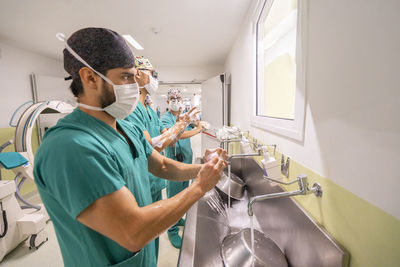 Doctors wearing masks washing hands in hospital