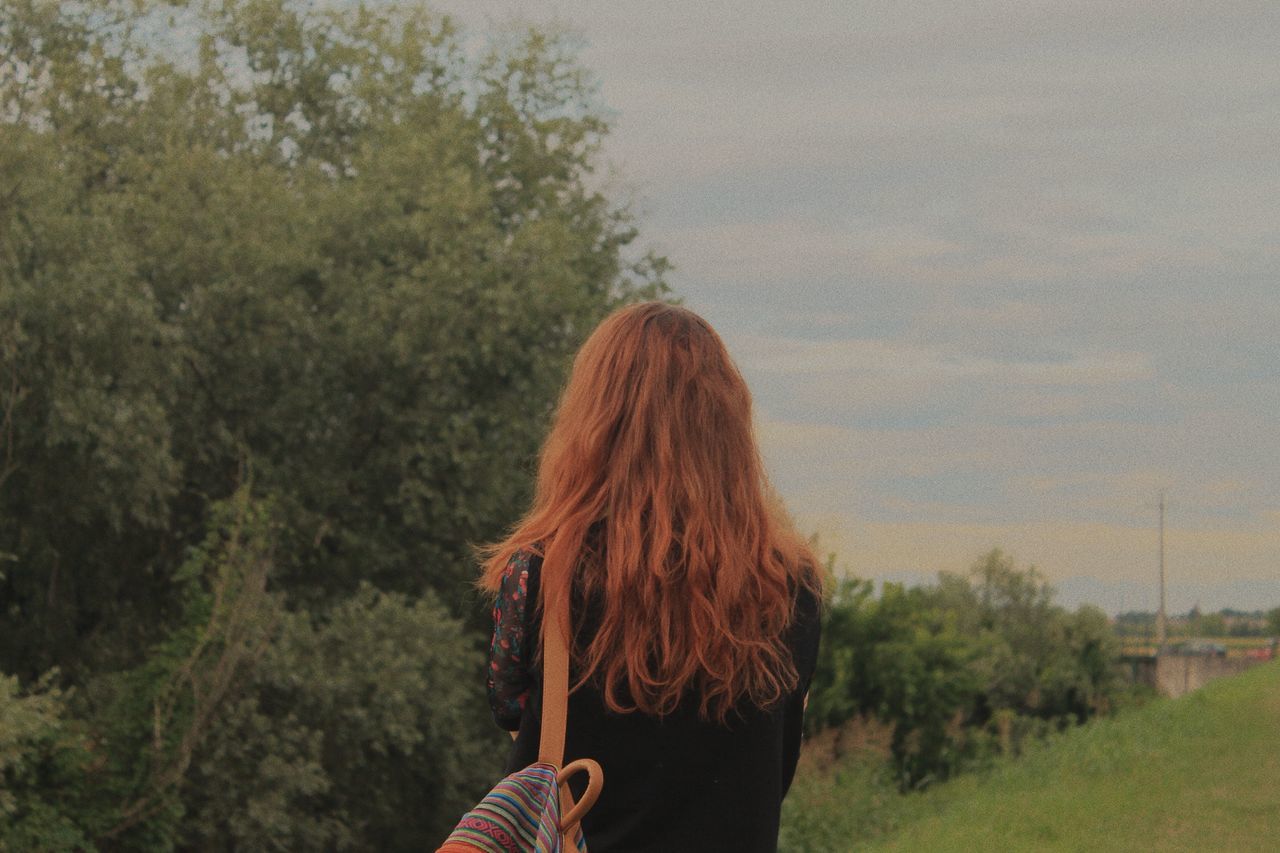 one person, tree, real people, rear view, long hair, hairstyle, plant, leisure activity, hair, women, lifestyles, nature, adult, brown hair, standing, sky, casual clothing, day, beauty in nature, outdoors, looking at view, human hair