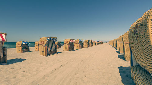 Hooded chairs on beach against clear blue sky