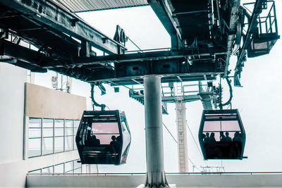 Silhouette people sitting in overhead cable car seen from glass window