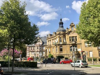 Cars on road by buildings against sky in city