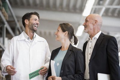 Happy male engineer and business people in manufacturing plant