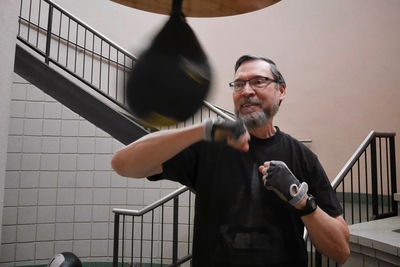Smiling senior man practicing boxing at gym