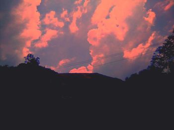 Low angle view of silhouette trees against dramatic sky