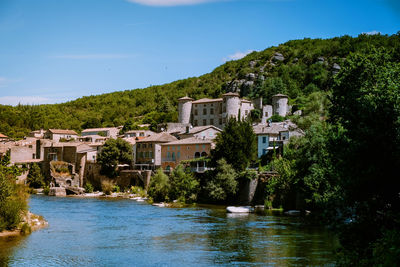 Buildings by river against blue sky