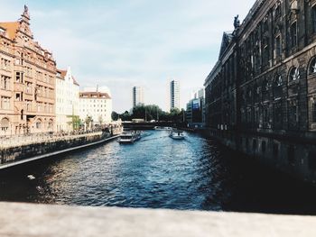 Canal amidst buildings in city against sky