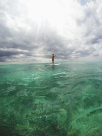 Man paddleboarding on sea against sky