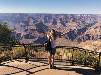 Rear view of woman standing on railing against mountain