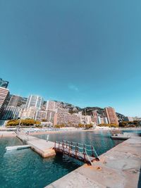 View of swimming pool by buildings against clear blue sky