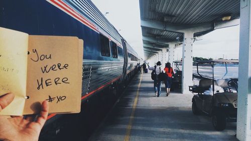 Cropped image of person holding book with text written on it at station