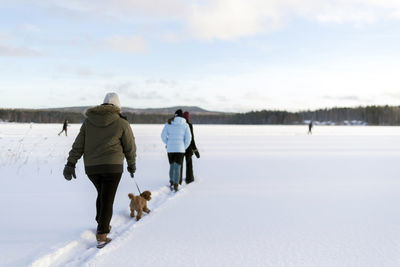 Rear view of people walking on snow covered landscape