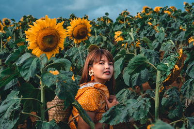 Portrait of smiling woman amidst yellow flowering plants