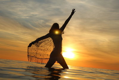 Silhouette person standing on beach against sky during sunset