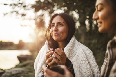 Female friends talking while drinking coffee in forest