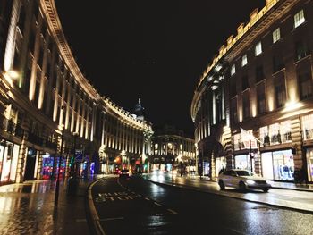 Cars on road amidst buildings in city at night