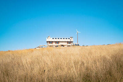 Built structure on field against clear blue sky