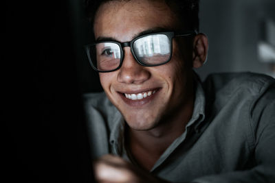 Portrait of young man wearing sunglasses against black background