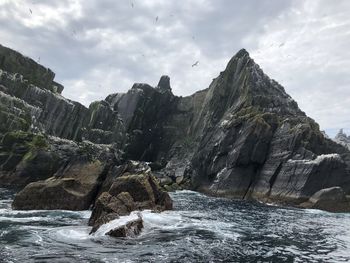 Rock formations by sea against sky