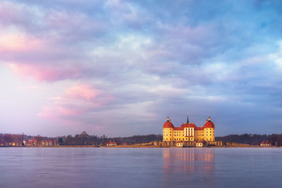 View of building by river against sky in city