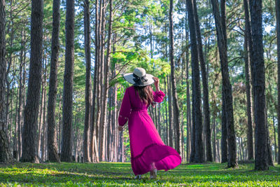 Woman standing by tree trunk in forest