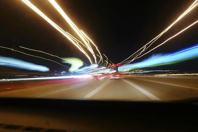 Light trails on highway against sky at night