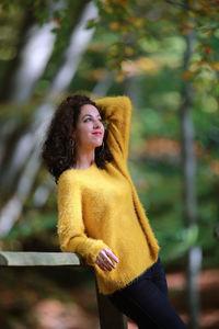 Young woman standing by tree in park