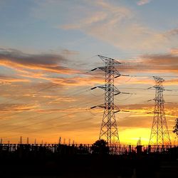 Low angle view of silhouette electricity pylon against sky during sunset