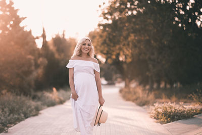 Happy pregnant woman walking at park