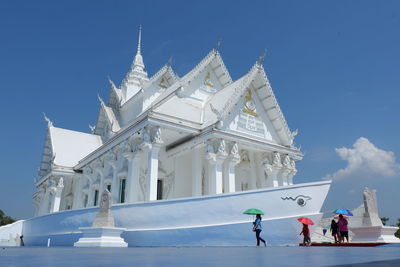 People outside temple building against sky