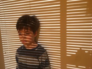 Boy standing against wall with shadow at home