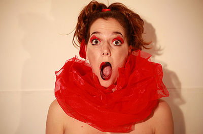 Close-up portrait of young woman against red wall