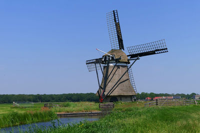 Traditional windmill on field against clear sky