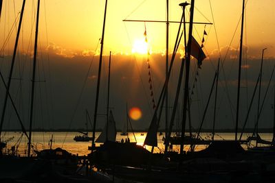 Sailboats moored at harbor during sunset