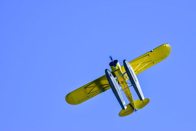 Low angle view of airplane against clear blue sky