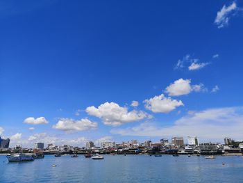 Buildings by sea against blue sky