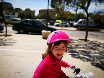 Portrait of smiling girl riding bicycle on street in city