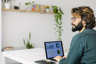 Thoughtful mature freelancer with laptop sitting at desk