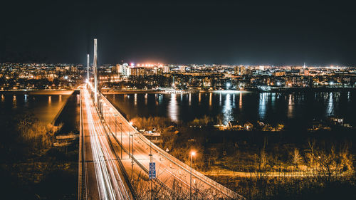 High angle view of illuminated bridge over river amidst buildings in city