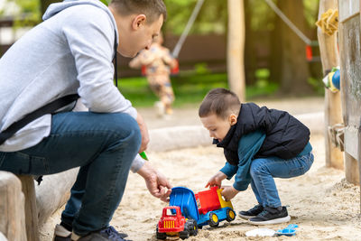 Little cute toddler boy three years old with dad plays in the sandbox on a spring day. 